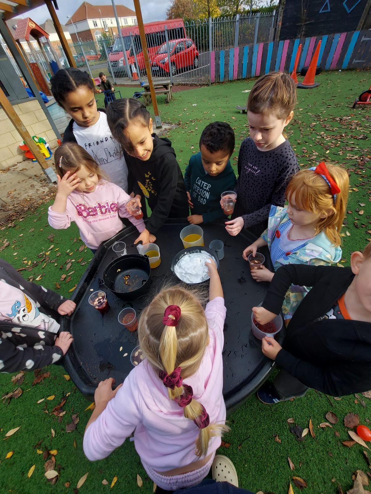 Large group of diverse children standing around a table working on a problem solving task