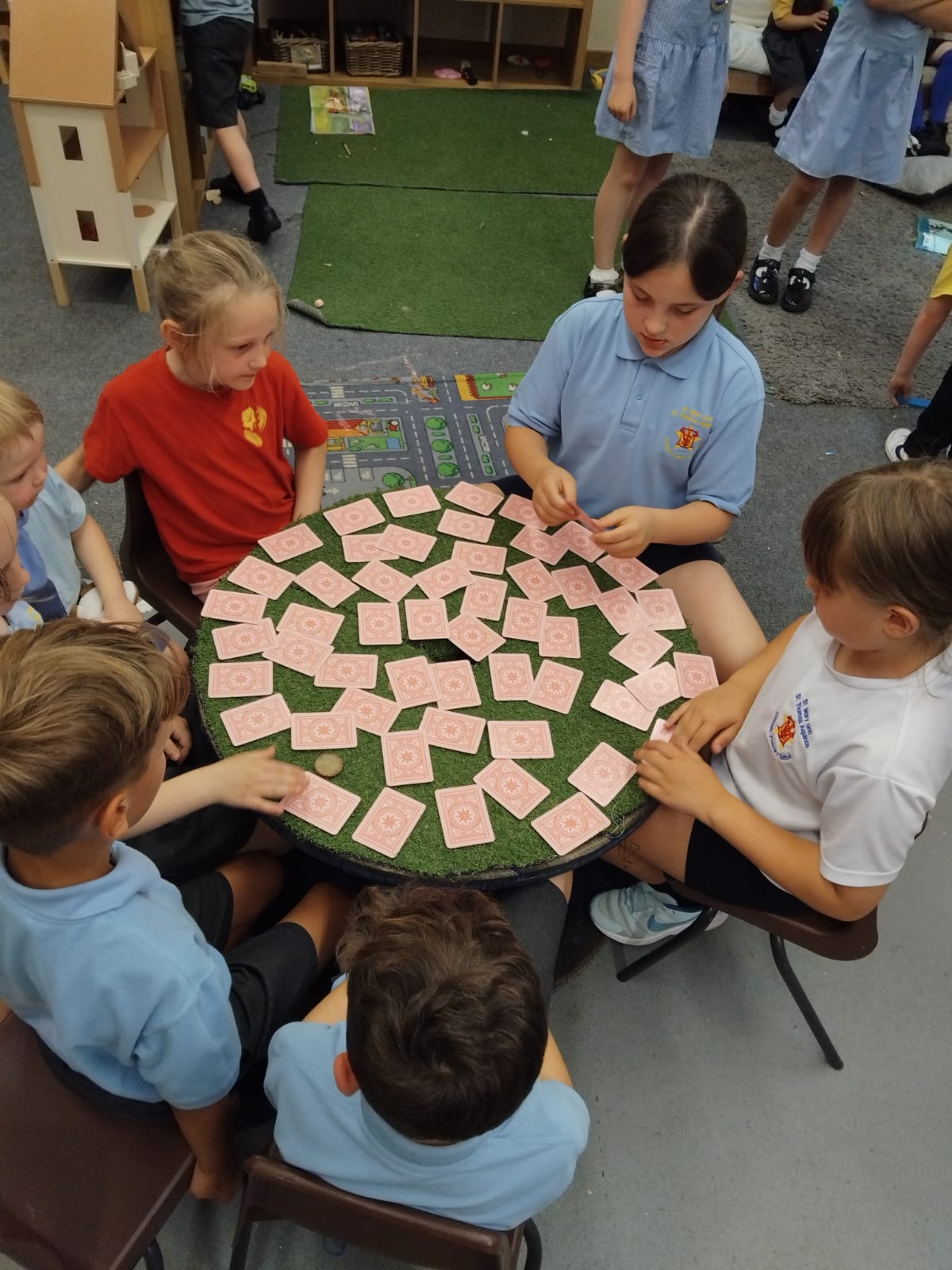Group of school aged children sitting around a table playing a card game